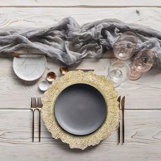 a table setting with plates, silverware and napkins on top of white wood