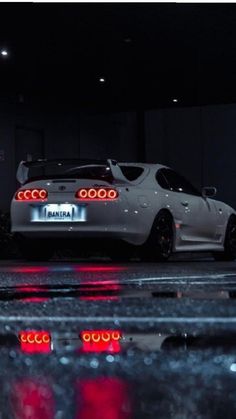 a white car parked in a garage with red lights on it's taillights