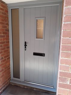 the front door is painted gray and has a brick wall