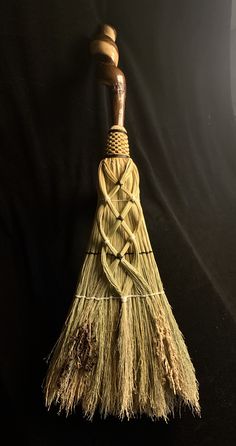 a broom that has been placed on a black background with a wooden handle and knoted ends