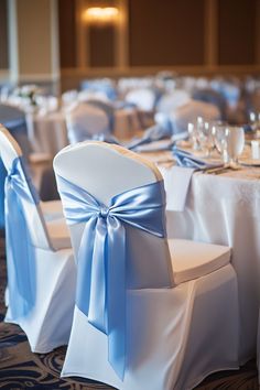 the chairs are decorated with blue sashes and white linens for an elegant event