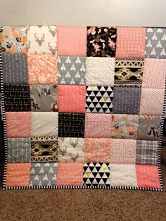 a patchwork quilt is on the floor in front of a white wall and brown carpet