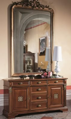 a large mirror sitting on top of a wooden dresser next to a lamp and table