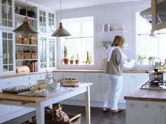 a woman standing in a kitchen preparing food