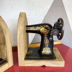 an old sewing machine is sitting on a wooden stand next to another antique sewing machine