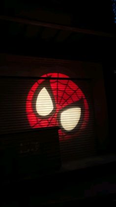 a red and white spider man logo is projected in the dark