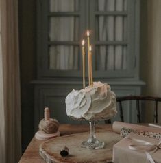 a cake with two candles sitting on top of a wooden table next to other items