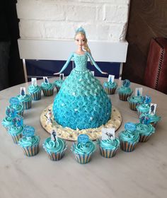 there is a cake and cupcakes on the table with blue frosting in the shape of a princess