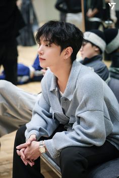 a young man sitting on top of a bench next to another person wearing a hat