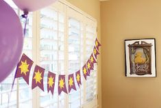 a room filled with balloons and pictures on the wall next to a bed in front of a window