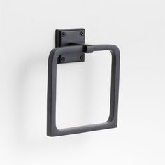 a black square shaped towel ring on a white wall with two holes in the middle