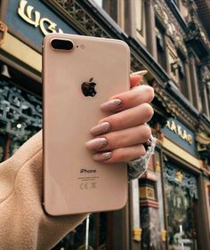 a woman's hand holding an iphone in front of a store