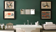 a bathroom with green walls and pictures on the wall above it, including a sink