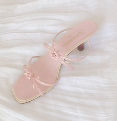 a pair of pink sandals on top of a white bed