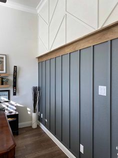 a room with gray walls and wood flooring on the wall, along with a wooden desk