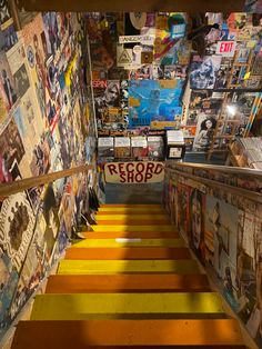 there is a yellow stair case with many pictures on the wall behind it and an empty sign that reads record shop