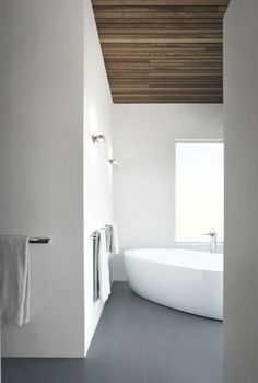 a white bath tub sitting under a wooden ceiling