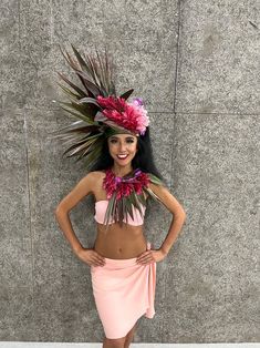 a woman in a pink skirt and flower headdress posing for the camera with her hands on her hips