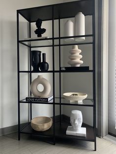 a shelf filled with vases and other items on top of a hard wood floor