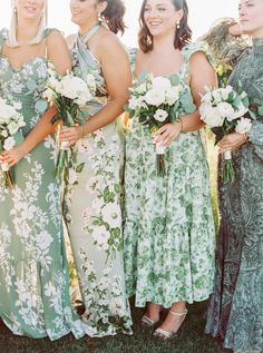 a group of women standing next to each other holding bouquets in their hands and smiling at the camera