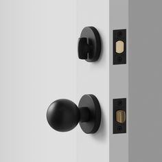 two black knobs on the side of a white door and one is brass or silver