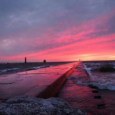 the sun is setting over the water at the beach