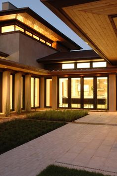 a modern house lit up at night with lights on the windows and grass in front