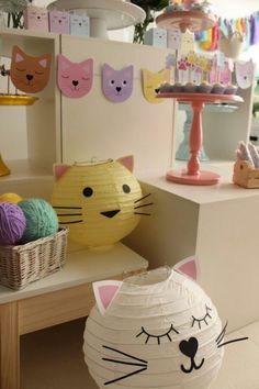 a cat paper lantern sitting on top of a table next to a basket filled with balls of yarn