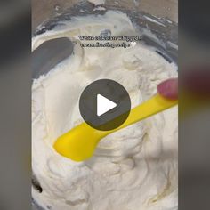 a mixing bowl filled with whipped cream and a yellow spoon in the middle of it