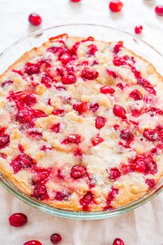 a pie with cranberry toppings in a glass dish on top of a table