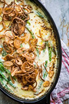 a casserole dish with asparagus, onions and other toppings on top