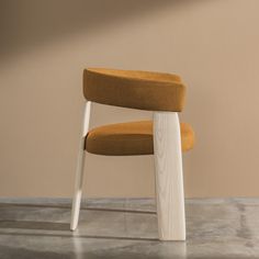 an orange chair sitting on top of a cement floor next to a wall with a wooden frame