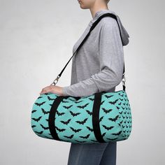 We just love this whimsical, colorful, sturdy duffel that comes in two sizes and is made in and ships from the USA! Lightweight and durable, this beautiful duffel features a gorgeous aqua blue background with creepy cute bats, and is a great way to express yourself!  Perfect for the gym, a weekend trip, a sleepover, a travel carry-on, schlepping your school supplies, or any other carryall needs!  Easy to carry with regular top handles or with the longer removable shoulder strap, these duffel bag Harajuku Style Black Halloween Bags, Black Novelty Bag For Everyday Use, Harajuku Black Bags For Halloween, Black Harajuku Style Halloween Bags, Cute Black Bags For Halloween, Casual Black Halloween Bag, Casual Black Bag For Halloween, Novelty Black School Bag, Novelty Black Bag For Gift