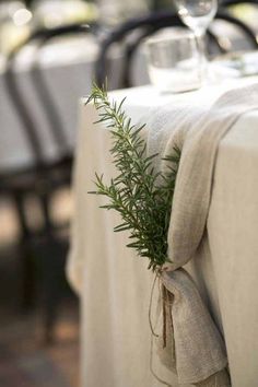 the table is set with white linens and greenery