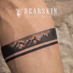 a man's arm with a tattoo on it that has mountains in the background