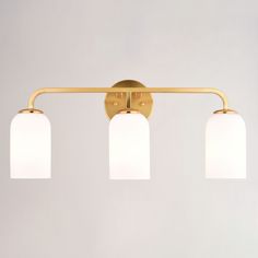 three light brass bathroom fixture with white glass shades on the top and bottom lights down