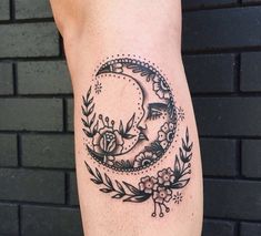 a woman's leg with a tattoo on it that has a crescent and flowers