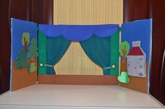 a paper cut out of a stage with curtains and trees on the side, in front of a window