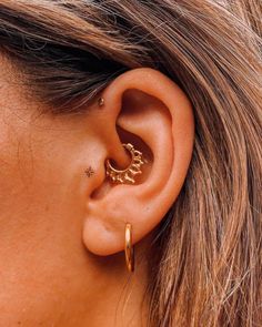 a close up of a person's ear with an earring in the shape of a crescent