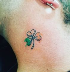 a man with a clover tattoo on his back shoulder and behind his neck is a four leaf clover