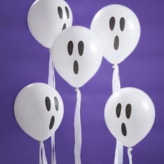 five white balloons with black faces and tassels hanging from them on a purple background