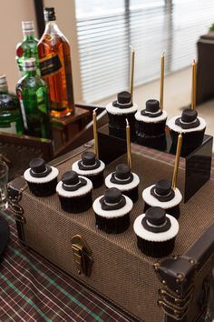 there are cupcakes with black and white frosting on the top, sitting on a suitcase