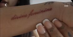 a woman holding her arm with the word divine feminine written on it