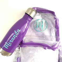 a purple water bottle sitting on top of a plastic bag next to a zippered pouch