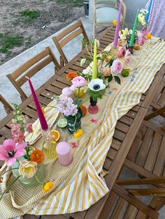 a long table with flowers and candles on it is set up for an outdoor party