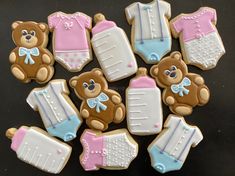 baby shower cookies decorated with teddy bears and onesuits on a black table top