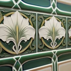 decorative tiles with white flowers on green and gold bordering the entire wall, in an art deco style