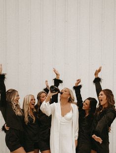 a group of women standing next to each other with their arms in the air and wearing black outfits