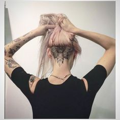 a woman with pink hair has tattoos on her back and is holding her hands behind her head