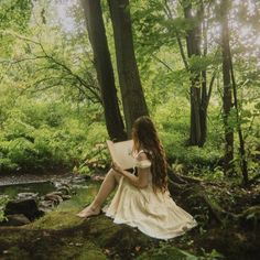 a woman sitting in the woods reading a book